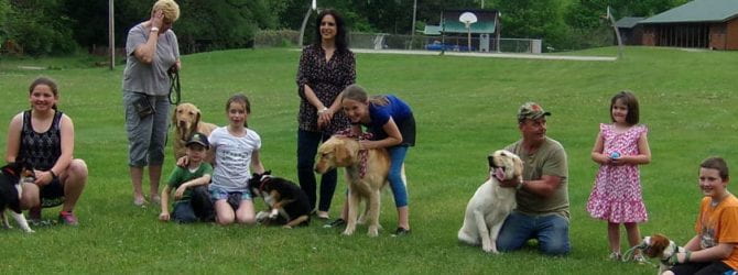 seven youth posing with their dogs and adult mentors