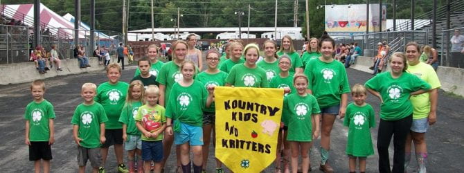 Kountry Kids and Critters participating in the 4-H parade with their banner and all wearing matching 4-H shirts.