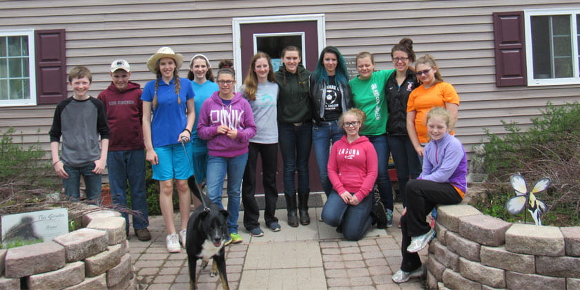 group of teens standing in front of an animal shelter with dogs they walked